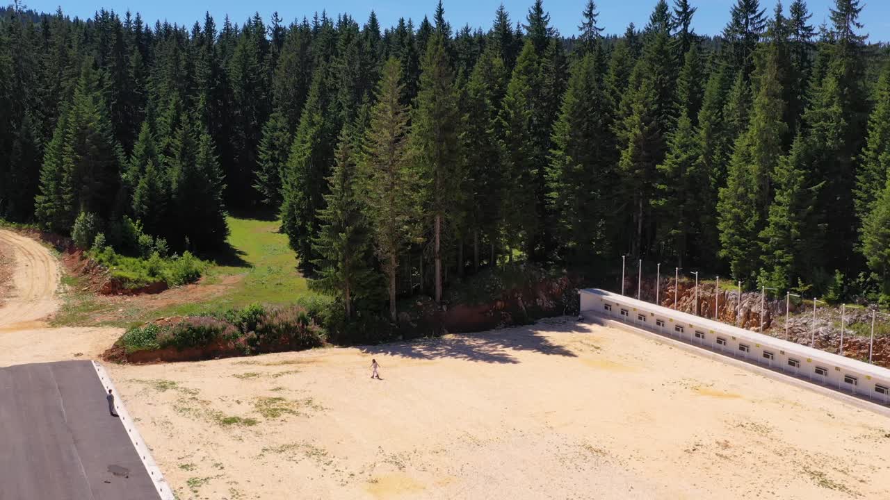 Roller skating and wark up ski warm-up track in Jahorina, Bosnia - Herzegovina during the summer, Aerial dolly out reveal shot