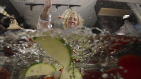 woman dropping vegetables into water