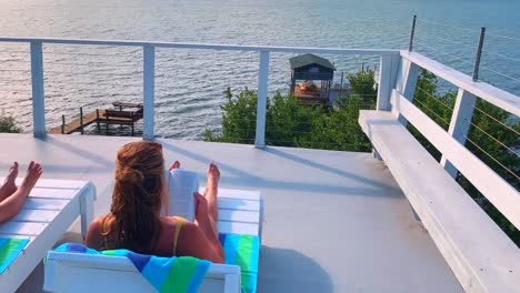 A-relaxing-scene-of-a-girl-sunbathing-and-reading-from-her-sundeck-overlooking-the-water