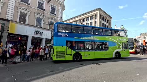 busy street with buses and waiting pedestrians