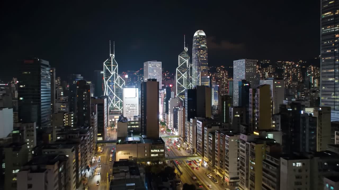 The vibrant city skyline glows at night with illuminated skyscrapers and busy streets. Cars move below, highlighting urban life and energy in this lively metropolis.
