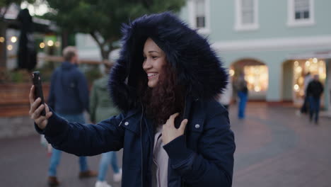 portrait of cheerful young mixed race woman smiling happy posing taking selfie photo using smartphone wearing fur coat