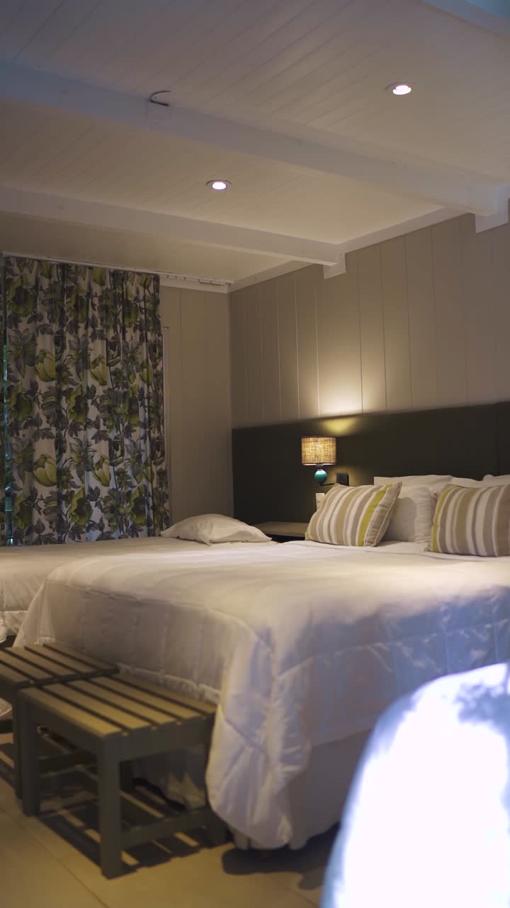 los reflectores que iluminan una elegante habitación de hotel con una cama doble y dos individuales, mostrando cortinas con patrones, un cabecera chic, crean un ambiente cálido y acogedor perfecto para una estancia relajada