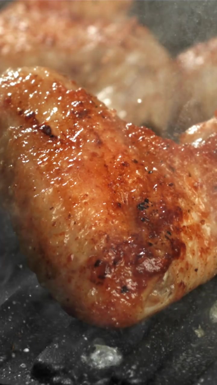 Primo piano di un'ala di pollo che sfrigola su una griglia calda