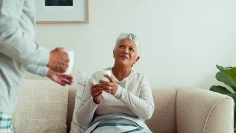 Senior-couple,-giving-and-drinking-coffee-on-sofa