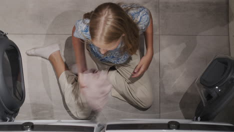 a teenage girl transfers clean clothes from the washing machine to the dryer. top view