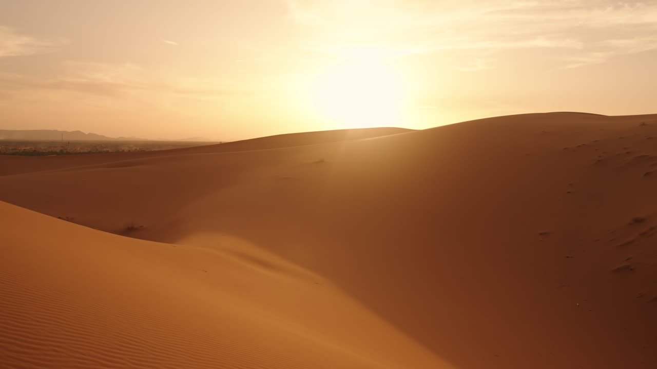 Golden sunlight casts long shadows on rippled Sahara sand textures