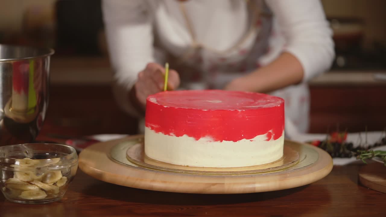 mujer decorando un hermoso pastel de capa roja y blanca
