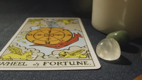 disparo de cerca de una persona que da una lectura de cartas del tarot colocando la rueda de la fortuna, el diablo y las cartas de juicio en la mesa