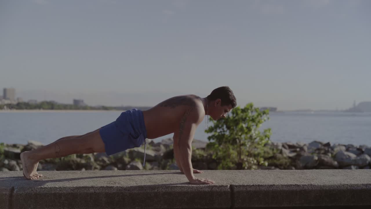 Man Doing Push-ups by the Waterfront with City Skyline