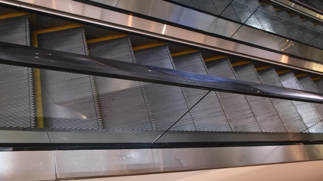 Two empty escalators, one going up and one going down inside a commercial building in a Southeast Asian city.