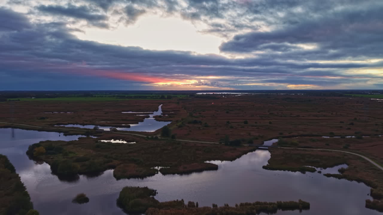 Vibrant sunset paints the marshlands in hues of orange and purple, showcasing nature's beauty in harmony during twilight hours