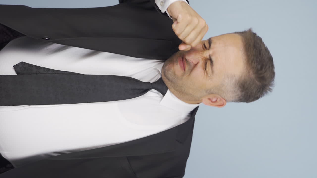 vídeo vertical de un hombre de negocios oliendo sudor expresando lo negativo a la cámara.