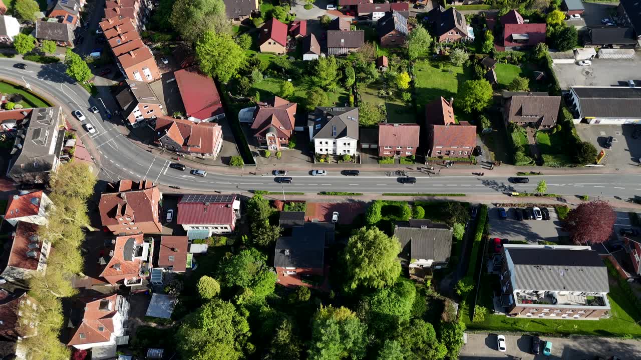 Traffic scene on street in german city with townhouses and green trees in spring. Sunny day in historic town. Aerial top down flyover shot.