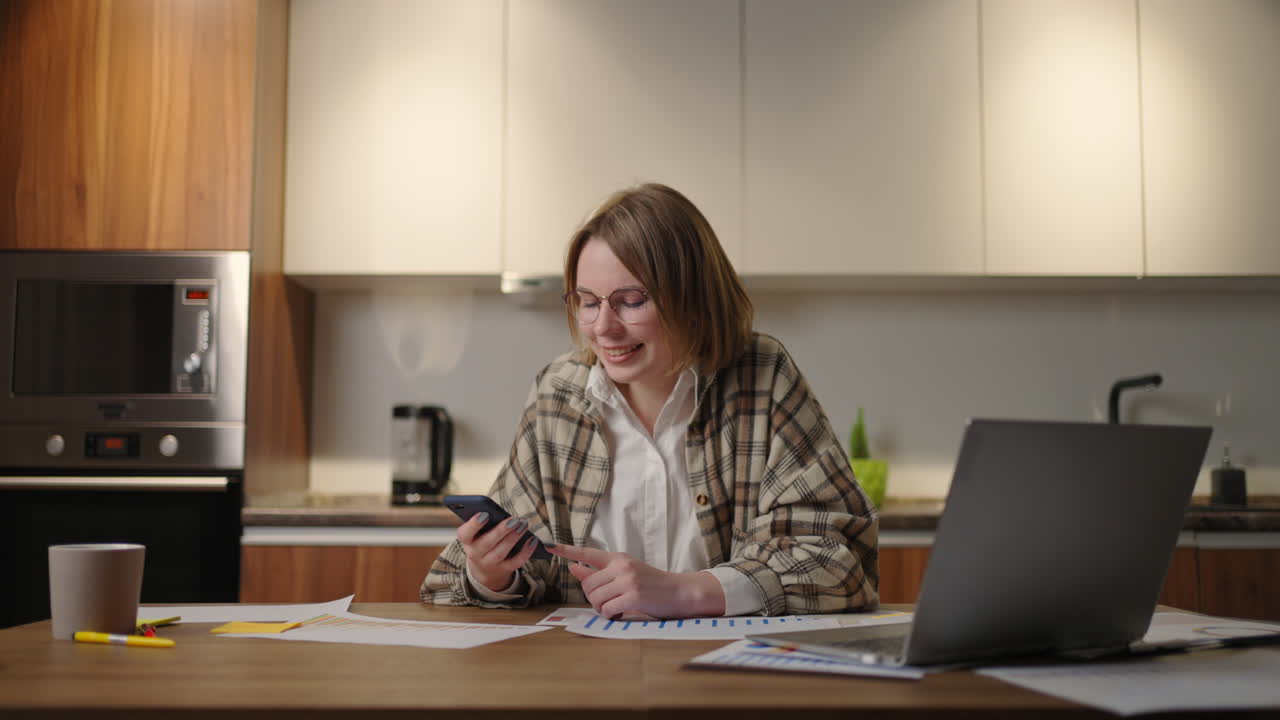 businesswoman holding modern smart phone texting message in office. Young female employee using modern mobile technology business app typing email on cell sitting at work desk.