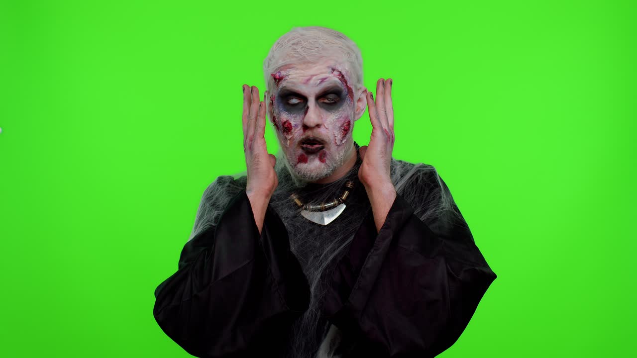 무서운 남자 할로윈 좀비는 놀라서 손을 들어 갑작스러운 승리에 충격을 받고 있습니다.