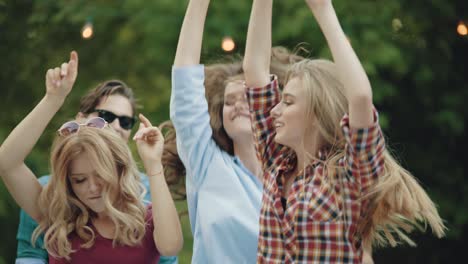 happy friends dancing, having fun and enjoying party outdoors.