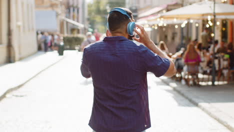Rear view of indian man tourist walking through the street outdoors looking searching for a way