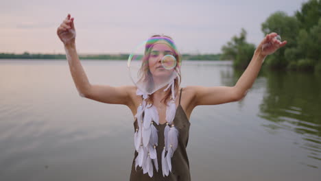 a young female artist shows a soap bubble show by blowing up large soap bubbles with her hands in slow motion