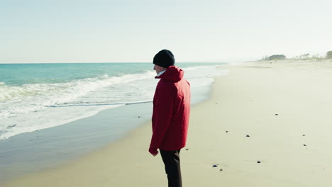 Elderly Man Throws Stones into the Sea During Winter