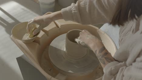 a woman doing pottery on the wheel