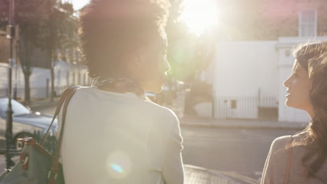 Two-beautiful-friends-walking-down-city-streets-having-fun-conversation-catching-up