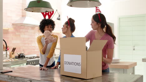 women friends wearing festive headbands packing donations in kitchen for christmas