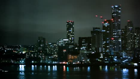 nightime time lapse of modern buildings at london skyline, waterfront skyscrapers, city lights