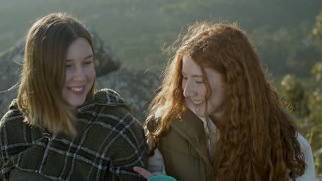 primer plano de dos chicas hablando y riendo mientras beben té caliente al aire libre