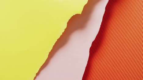 video of close up of torn pieces of yellow, pink and orange striped paper background