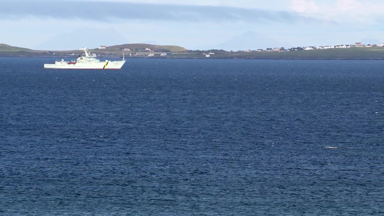 Static shot of a Royal Navy or Coastguard fisheries patrol vessel, sailing on a windy day through Broadbay near Stornoway, part of the Outer Hebrides of Scotland.