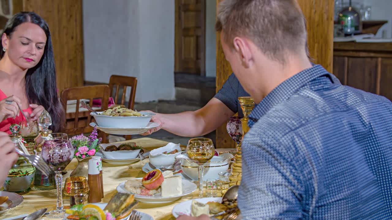 Two young couples eat together at table. Slow motion