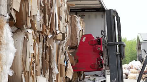 Fork-lift-at-recycling-center-unloading-bale-of-cardboard,-ready-for-processing