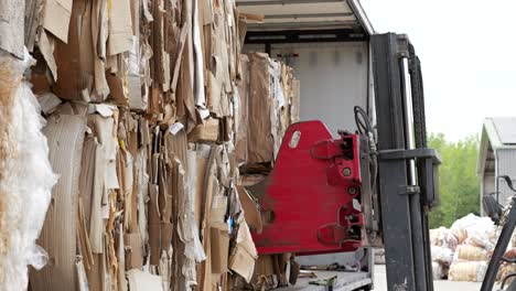 elevador de horquilla en el centro de reciclaje descargando balas de cartón, listas para el procesamiento
