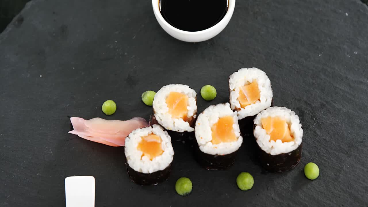 sushi maki servido em ardósia de pedra cinzenta com molho de soja