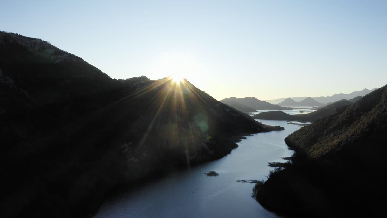 AERIAL - Silhouette of mountains at sunrise, Lake Skadar, Montenegro, reverse