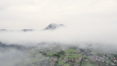 Vuelo-Aéreo-A-Través-De-Las-Nubes-Para-Revelar-Un-Pequeño-Pueblo-Debajo-En-Valle-De-Bravo,-México.