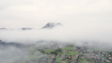 vuelo aéreo a través de las nubes para revelar una pequeña ciudad abajo en valle de bravo, méxico