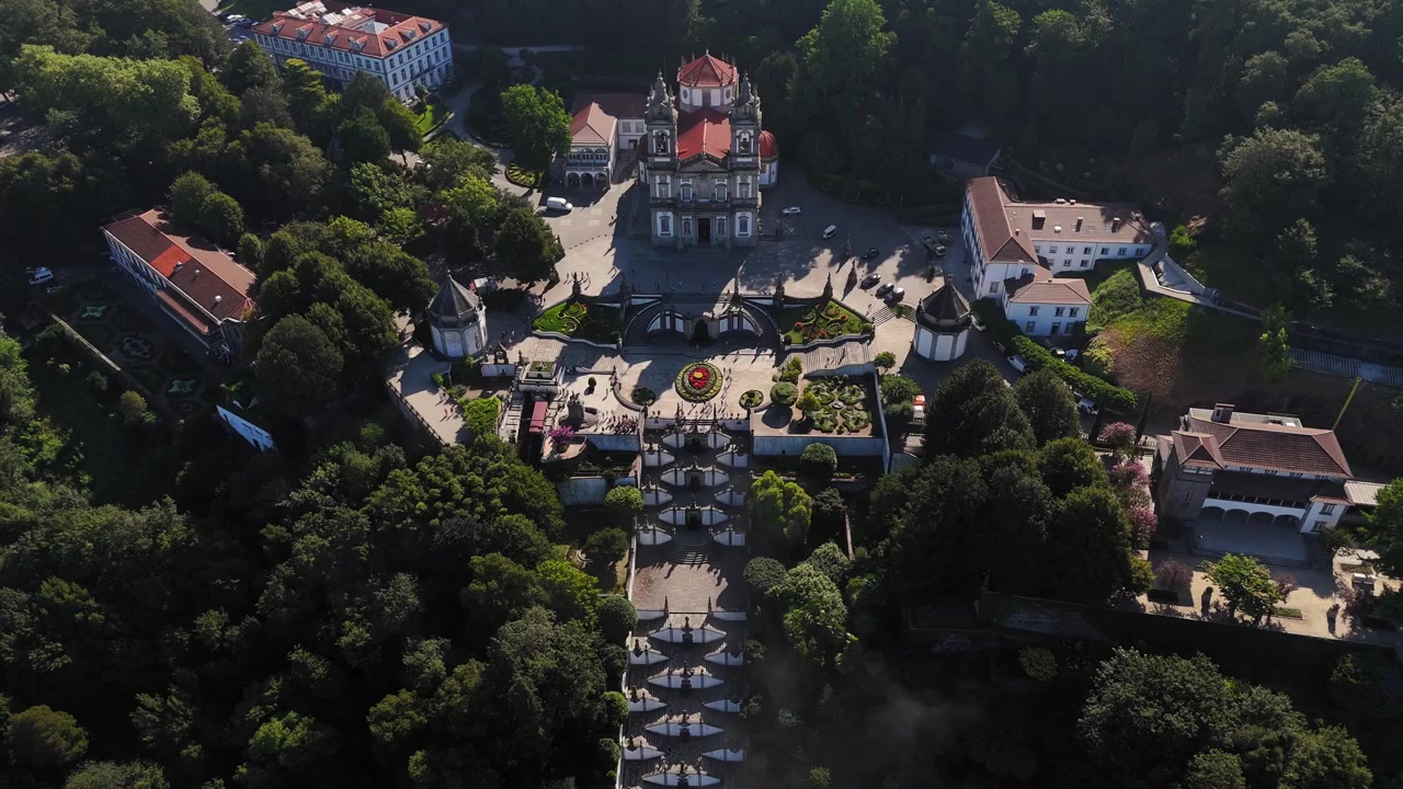Bom Jesus do Monte, Braga, Portogallo, che mostra l'iconica scalinata, la rigogliosa vegetazione forestale circostante e gli edifici storici alla luce del mattino - drone