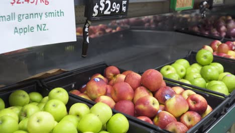 tracking shot of bins of apples on supermarket shelves