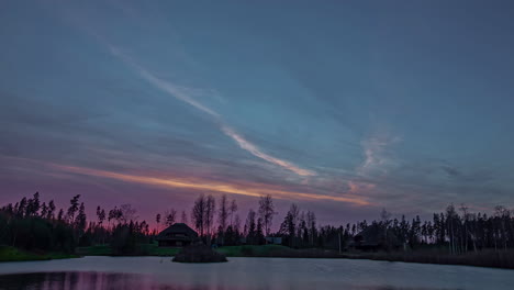 rural cabin in a winter landscape at sunset with the lake water freezing on the ice - colorful, wide angle time lapse