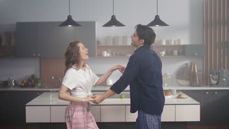 Laughing-couple-dancing-at-domestic-kitchen.-Two-people-enjoying-time-together.