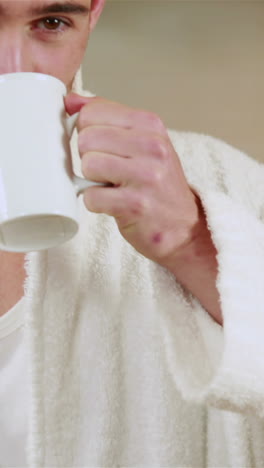 hombre guapo bebiendo café en bata de baño