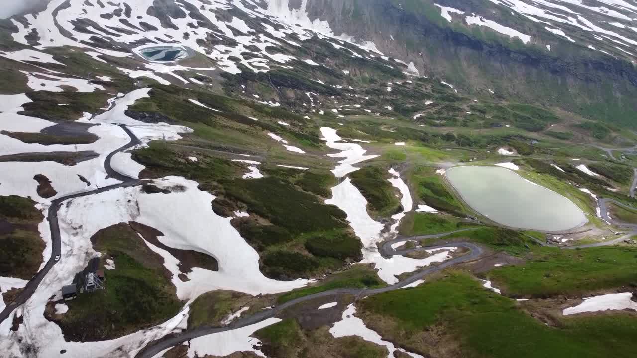 Dronekuva kesäisestä hiihtokeskuksesta, jossa on vesiallas ja lumilaikkuja.