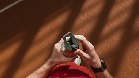 person holding a metal water bottle on an athletic track
