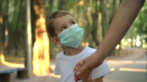 madre e hijo con máscaras médicas caminan en el parque 02