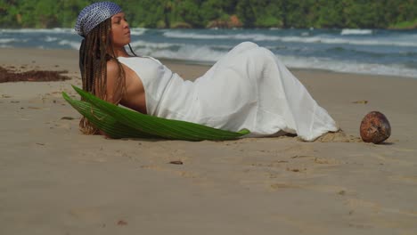 ascending pan of a young girl laying in the sand on the beach