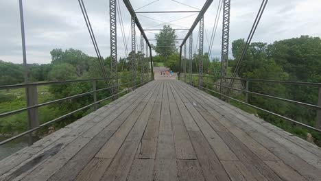 pov driving across a turn of the century truss bridge with a wooden deck over split rock creek in palisades state park in rural south dakota, usa