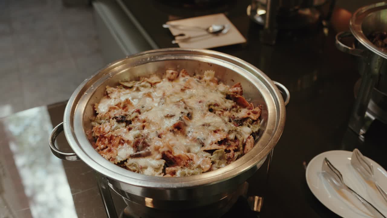 hot cheesy pasta dish in buffet tray ready for self service