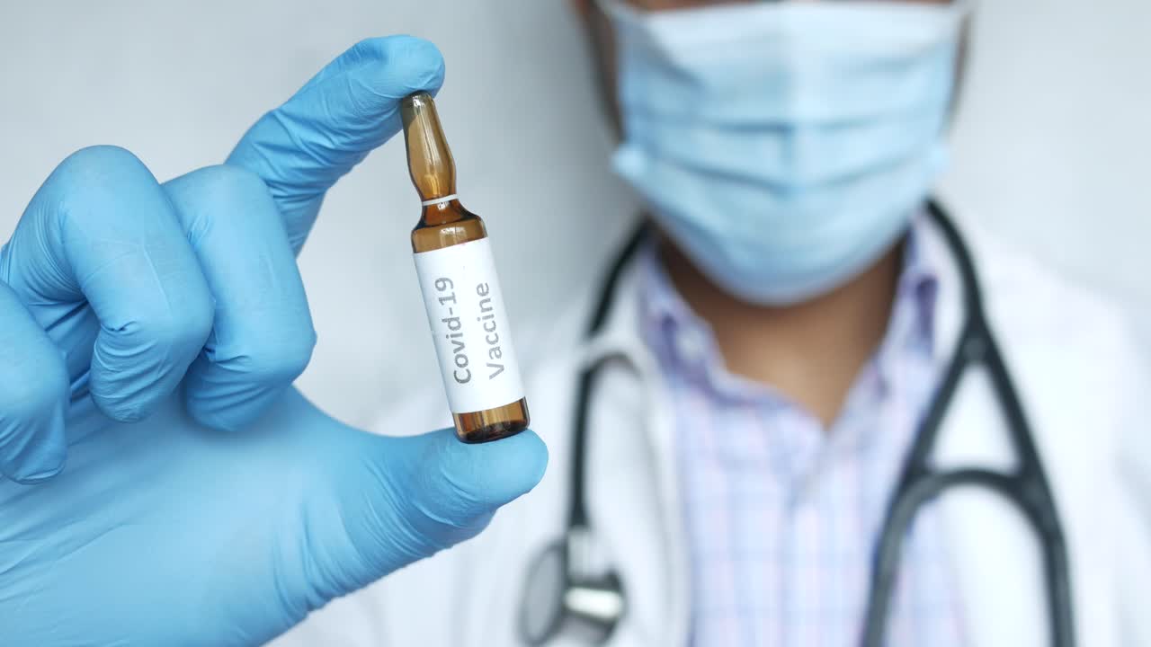médico que sostiene el vial de la vacuna contra la covid-19